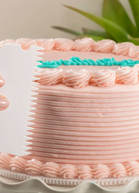 Close-up of cake edger creating a decorative frosting pattern on a cake